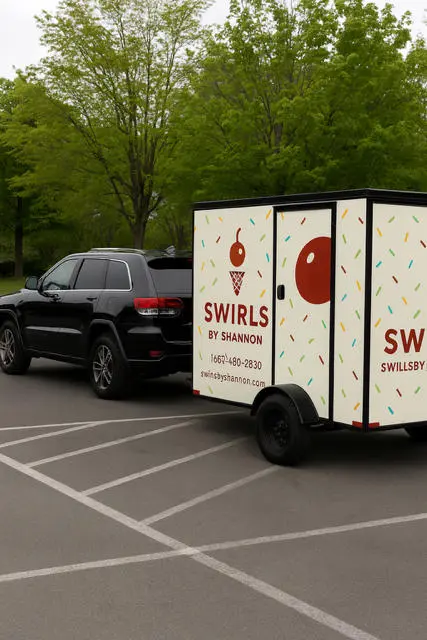 A black SUV towing a colorful trailer with ice cream swirls graphics.